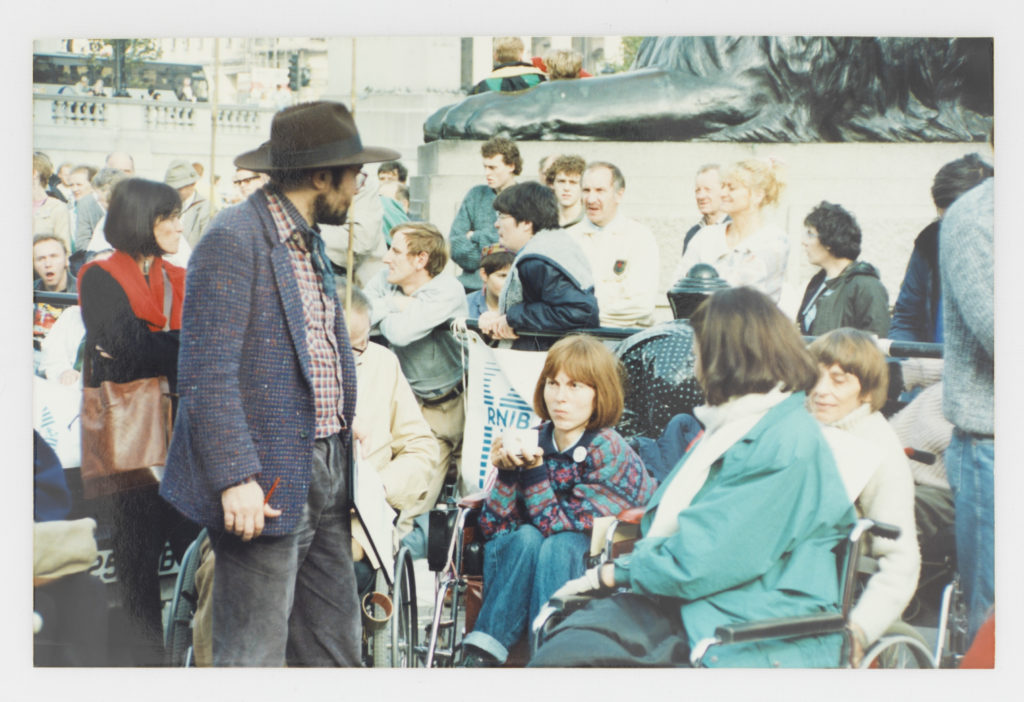 A 1980s disability rights gathering in Trafalgar Square, wheelchair users among the crowd